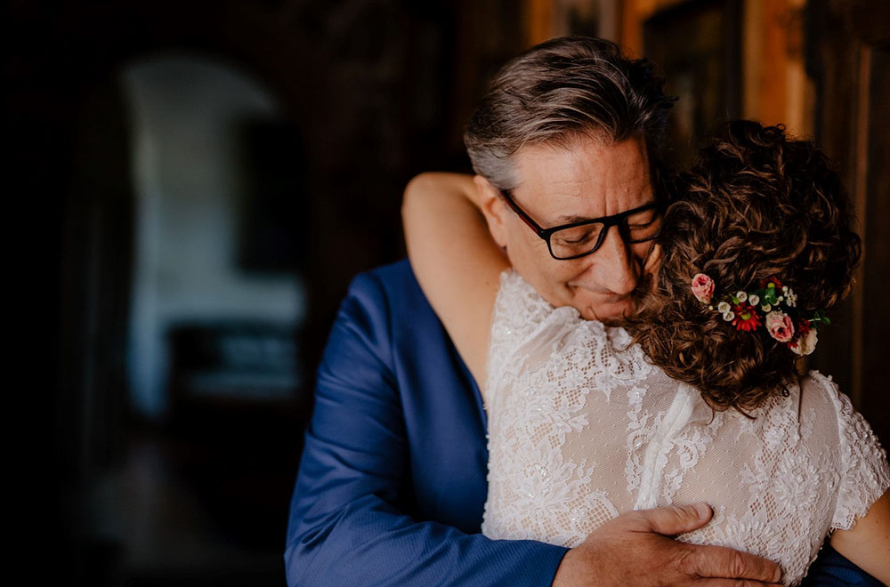 La sposa abbraccia il papà - acconciatura con fiori nei capelli